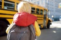 Pupil with schoolbag with yellow school bus on background Royalty Free Stock Photo