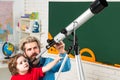 Pupil watching stars with a teacher. Astronomy telescope. Happy cute industrious child is sitting at a desk indoors
