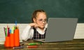 Pupil working on laptop computer over blackboard background. School kids. Teachers day. Funny little child having fun on Royalty Free Stock Photo