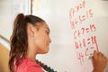 Pupil writing on the board at elementary school maths class