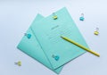 Top view of two pupils copybooks with form to sign in: name, surname, grade, etc. with yellow pencil and paper clips on white back