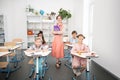 Four diligent pupils sitting at the desks near teacher