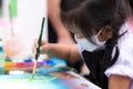 Pupils girl are concentrating on drawing and painting with brush and watercolor on the canvas.