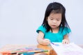 Pupils girl are concentrating on drawing and painting with colored pencils crayon on art paper book. Asian little child learning