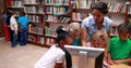 Pupils looking at the computer in library with their teacher