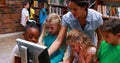 Pupils looking at the computer in library with their teacher