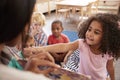 Pupils At Montessori School Looking At Book With Teacher Royalty Free Stock Photo