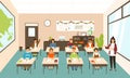 Pupils sitting at desks in modern classroom, young female teacher teaching them. Elementary school boys and girls Royalty Free Stock Photo