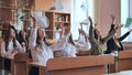 Pupils sitting at their desks in the classroom throw notebooks up. Group of students to complete academic year Royalty Free Stock Photo