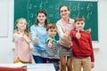 Pupils and teacher in class room of school showing thumbs-up