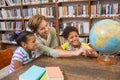 Pupils and teacher looking at globe in library Royalty Free Stock Photo