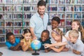 Pupils and teacher looking at globe in library Royalty Free Stock Photo