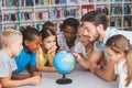 Pupils and teacher looking at globe in library Royalty Free Stock Photo