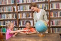 Pupils and teacher looking at globe in library Royalty Free Stock Photo