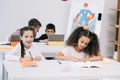 Pupils writing in exercise books and using digital tablets during lesson Royalty Free Stock Photo