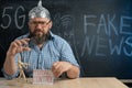 a puppet in the hands of a man in a foil hat sitting at the table. Man controls people and consciousness. Manipulations Royalty Free Stock Photo