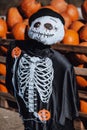 Puppet in spooky costume with heap of pumpkin in background at halloween