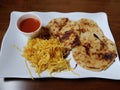 Pupusa or tortilla stuffed with cheese on plate with cabbage and tomato sauce