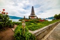 Pura Ulun Danu Bratan temple. Balinese landmark. Red and yellow flowers in the foreground. Bratan lake, Bali, Indonesia Royalty Free Stock Photo