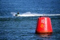 Purbeck, Dorset, UK - Jun 02 2018: Man on a jet ski speeding past a 10 knot speed limit marker buoy Royalty Free Stock Photo