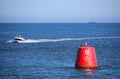 Purbeck, Dorset, UK - Jun 02 2018: Motorboat speeding past a 10 knot speed limit marker buoy Royalty Free Stock Photo