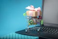 Daily purchases and gifts in the shopping cart on the laptop keyboard on a blue background. Shopping in online stores Royalty Free Stock Photo