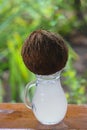 Pure coconut water drips from coconut into pitcher