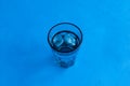 Pure drinking water with ice in a transparent blue glass on a blue background. Top view, selective focus, copy space Royalty Free Stock Photo