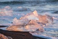 Pure Ice Shining on Black Volcanic Sand at Sunset. Icebergs from Glacier in Sun Rays. Clear Ice in Ocean Waves. Famous Royalty Free Stock Photo