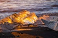 Pure Ice Shining on Black Volcanic Sand at Sunset. Icebergs from Glacier in Sun Rays. Clear Ice in Ocean Waves. Famous Royalty Free Stock Photo