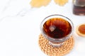 Pure maple syrup with leaf, glass bottle, and wooden spoon on white