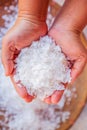 Pure white crystals salt, rock salt in women hands on crystals backgrounds. Top view, close-up. Traditional rock salt making of Bo