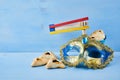 Purim celebration concept with hamantashen cookies, Purim mask and toy noisemaker on blue background