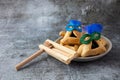 Purim celebration concept with hamantashen cookies, Purim mask and toy noisemaker on grey background