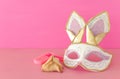 Purim celebration concept jewish carnival holiday with cute rabbit mask, noisemaker and hamantash cookies over wooden table