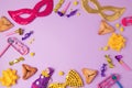 Purim holiday concept with carnival mask, hamans ears cookies and party supplies on purple background.