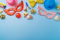 Purim holiday concept with carnival mask, noisemaker, hamantaschen cookies and party supplies on blue background. Top view, flat Royalty Free Stock Photo