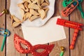 Purim holiday concept with greeting card and hamantaschen cookies on wooden background.
