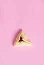 One Hamentashen, Ozen Haman, Purim cookie on pink background for Jewish holiday Purim.