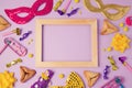 Purim holiday concept with wooden frame, carnival mask and hamans ears cookies on purple background. Top view from above.