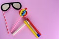 Purim Jewish celebration holiday greeting card. Cute glasses paper mask, colorful wooden noisemakers on pink background.
