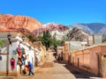 Purmamarca town view with woman crossing the street and Cerro de los Siete Colores hills background