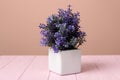 Purple artificial plant in white flower pot on wooden table