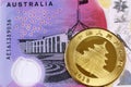 A purple Australian five dollar bill with a shiny gold Chinese coin