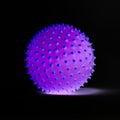 Purple ball with blue spikes glowing on black background Royalty Free Stock Photo