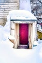 Purple basement door of home amidst mounds of fresh white snow in winter