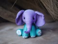 A purple and blue stuffed elephant sitting next to a pile of hay. Generative AI image.