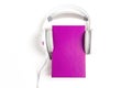 Purple book with a white headphones on it on white background.