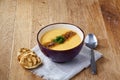 Ceramic bowl of pumpkin soup on napkin over rustic wooden background, close-up, selective focus, top view. Royalty Free Stock Photo