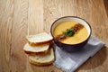 Ceramic bowl of pumpkin soup on napkin over rustic wooden background, close-up, selective focus, top view. Royalty Free Stock Photo